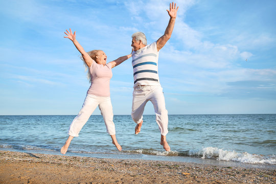 Happy jumping mature couple at sea resort