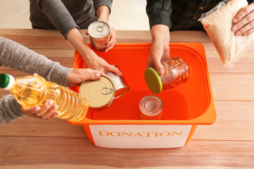 Volunteers putting donation food into box at table