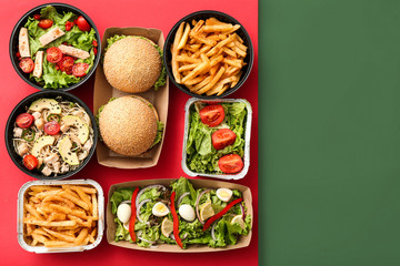 Containers with delicious food on color background
