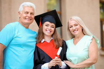 Happy young woman with her parents on graduation day