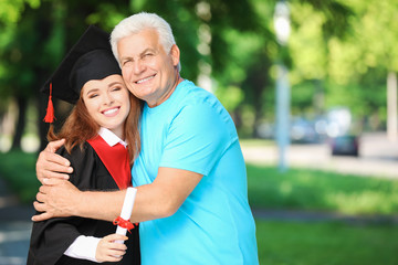 Happy young woman with her father on graduation day