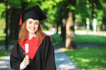 Happy young woman with diploma on graduation day