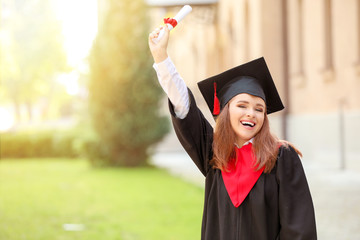 Happy young woman with diploma on graduation day