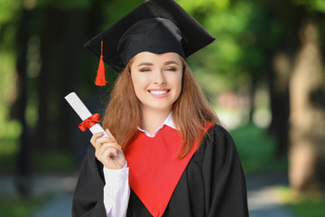 Happy young woman with diploma on graduation day