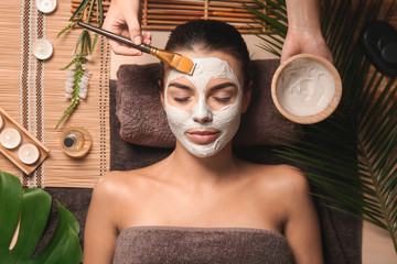 Cosmetologist applying mask on woman's face in spa salon
