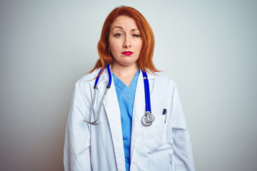 Young redhead doctor woman using stethoscope over white isolated background looking sleepy and tired, exhausted for fatigue and hangover, lazy eyes in the morning.