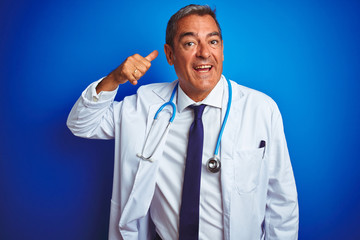 Handsome middle age doctor man wearing stethoscope over isolated blue background smiling doing phone gesture with hand and fingers like talking on the telephone. Communicating concepts.