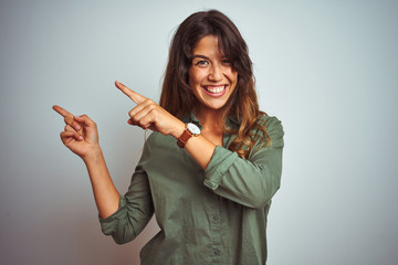 Young beautiful woman wearing green shirt standing over grey isolated background smiling and...