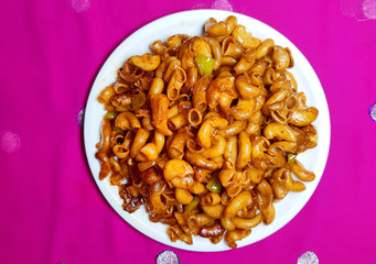 Homemade macaroni pasta in white plate on dark background.