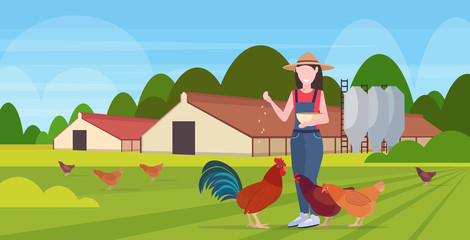 Obraz na płótnie Canvas woman farmer feeding chicken and rooster free range poultry breeding farming agriculture concept barn building countryside landscape background flat full length horizontal