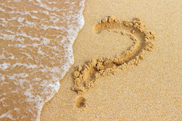 Question mark drawn on golden sand top view, copy space