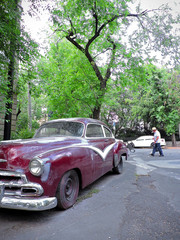 Fototapeta premium An old red car parked in the street seen in perspective.