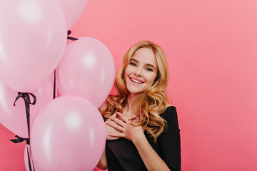 Studio portrait of glad white birthday girl. Enthusiastic blonde woman in black attire waiting for party and laughing.