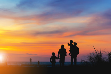 Fototapeta na wymiar Silhouette of Grandfather grandmother granddaughter and grandchild looking sun down and walking on the beach evening sunset background, Happy family concept
