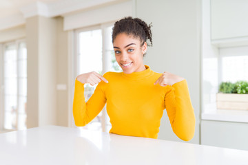 Beautiful african american woman with afro hair wearing a casual yellow sweater looking confident...