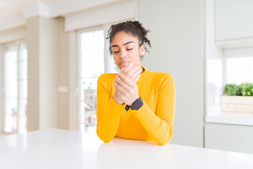 Beautiful african american woman with afro hair wearing a casual yellow sweater Suffering pain on...