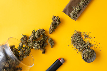 Fresh marihuana. Top view. Cannabis buds on yellow background. Blunt and Lighters. CBD and THC on...