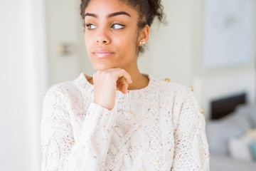 Fototapeta na wymiar Beautiful young african american woman with afro hair wearing casual sweater with hand on chin thinking about question, pensive expression. Smiling with thoughtful face. Doubt concept.