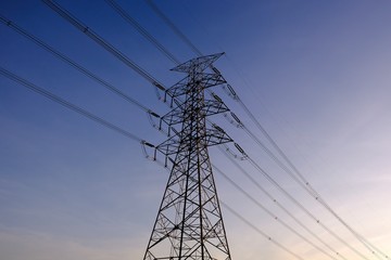 High voltage electrical power transmission tower on background of blue sky