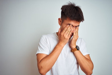 Young asian chinese man wearing t-shirt standing over isolated white background rubbing eyes for fatigue and headache, sleepy and tired expression. Vision problem