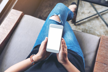 Top view mockup image of woman holding white mobile phone with blank screen while sitting in cafe
