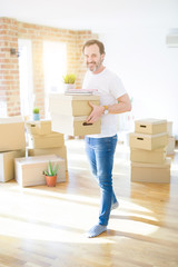 Fototapeta na wymiar Handsome middle age senior man smiling happy moving to a new house, packing and holding cardboard boxes