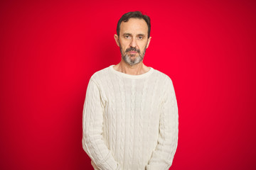 Handsome middle age senior man with grey hair over isolated red background Relaxed with serious expression on face. Simple and natural looking at the camera.