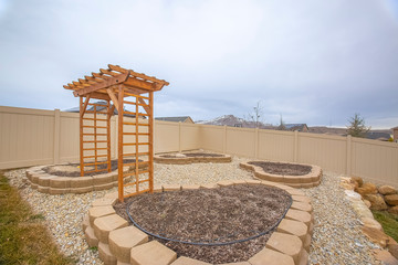 Heart shaped planting beds and wooden arbor at the yard of a home
