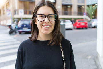 Beautiful young brunette woman smiling excited walking down the city streets, happy and confident...