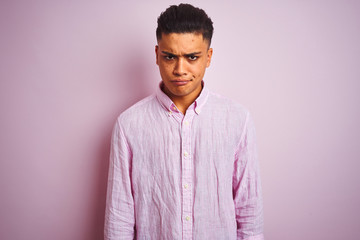 Young brazilian man wearing shirt standing over isolated pink background skeptic and nervous, frowning upset because of problem. Negative person.