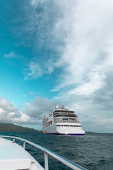 Cruise ship viewed over rail of smaller boat on ocean