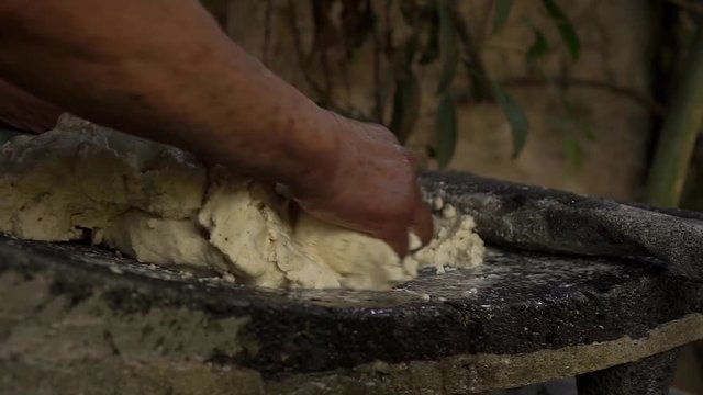 Mexican woman from Cuetzalan making authentic tortilla dough in a typical stone &ldquo;metate&rdquo;