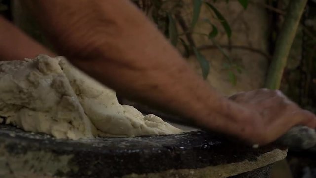 Mexican woman from Cuetzalan making authentic tortilla dough in a typical stone &ldquo;metate&rdquo;
