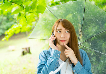 梅雨　傘をさして電話する女性