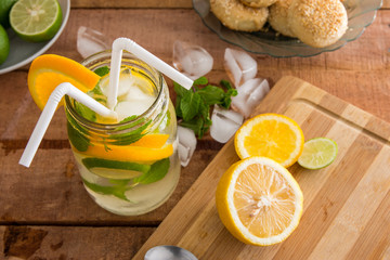 refreshing summer fruit drink with orange, lemon and mint on wooden benchtop.