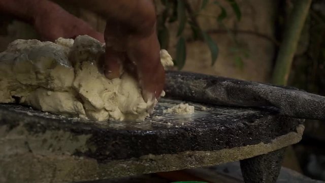 Mexican woman from Cuetzalan making authentic tortilla dough in a typical stone “metate”