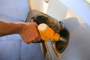 Man refills car, holds a filling gun in his hand