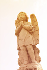 Beautiful angelic winged cherub. Close up of garden cherub angel statue with wings carved from...