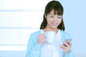 スマートフォンとコーヒーカップを持つ女性