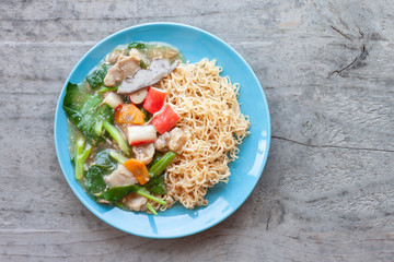 Fried noodle with pork, chinese kale and carrot thai call Rad Na in blue plate on wooden table.
