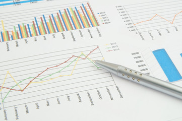 Business concept, silver pen on financial charts and graphs