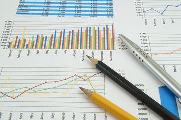 BusinBusiness concept, silver pen and pencils on financial charts and graphsess concept, magnifying...
