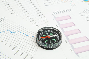 Navigation in financial world, compass on financial charts and graphs