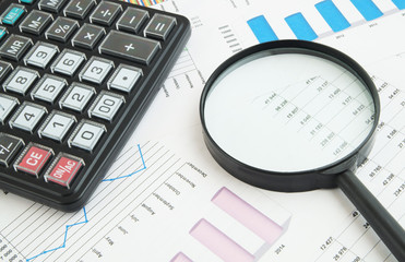 Business concept, calculator and magnifying glass on financial charts