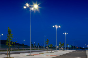 big modern empty parking lot with modern bright LED street lights at night