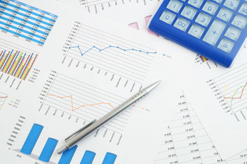 Business concept, calculator and silver pen on financial charts and graphs