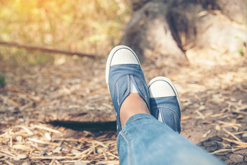 Hiking shoes young woman traveler sit down on summer park.focus on blue sneaker shoes and jeans on pathway. active activity vacation on hike mountain resting with walking way. Young traveler concept.