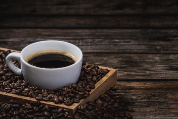 cup of coffee with beans on wooden table