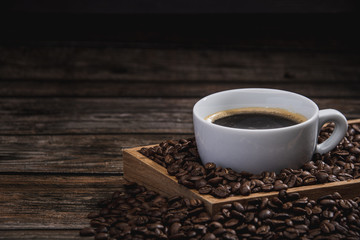 cup of coffee with beans on wooden table