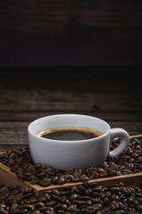 cup of coffee with beans on wooden table